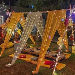 A closer look at the canopy seating arrangement, made with bamboo poles and draped with yellow and white fabric and fairy lights.
