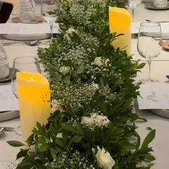 A closer look at the texture and detail within our greenery table runner. The combination of different leaves, delicate baby's breath, and soft white roses adds depth and sophistication to the tablescape.