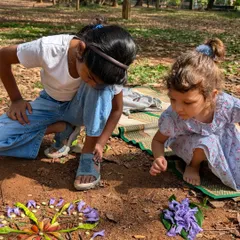 Two little artists collaborating on a beautiful flower mandala on the ground. This activity encourages teamwork and an appreciation for natural colors and patterns.