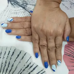 A bold blue manicure with a mix of solid royal blue and a light blue and white wave pattern on the accent nails. This is a fun, nautical-inspired look.