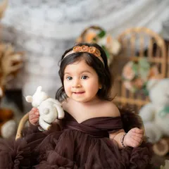 A close-up portrait of a beautiful baby girl holding her teddy bear. Sitter sessions are perfect for capturing those chubby cheeks and curious eyes.