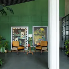 Another view of the Primus lounge, highlighting our custom designed armchairs with cane weaving against a rich green wall. The design blends natural materials and soothing colors to foster a sense of well being.