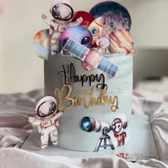 An out-of-this-world space-themed cake for an aspiring astronaut. It's decorated with planets, rockets, satellites, and little astronauts, all set against a cool grey-blue galaxy frosting.