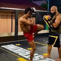 Step by step, we build a fighter. A student practicing a knee strike on the pads, a crucial weapon in Muay Thai and MMA.