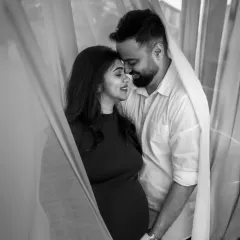 Wrapped in a soft curtain of light, this couple shares a private, loving moment. Our black and white couple portraits are perfect for creating timeless, emotional keepsakes of your pregnancy journey.