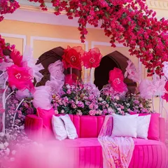 A dreamy welcome to a 'gulabi' brunch. A plush pink sofa sits under a massive arch of fuchsia bougainvillea, creating a photo op that's pure floral fantasy.