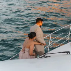 A candid shot of the couple on their private yacht, looking out at the ocean together as the sun sets, creating a romantic and cinematic feel.