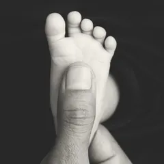 This black and white version emphasizes the contrast in size and the delicate perfection of a newborn's foot. It's a simple, yet profound, image.