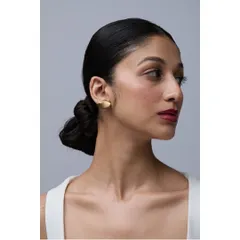 This close-up profile shot beautifully showcases a modern, minimalist gold earring. The clean background, soft lighting, and the model's elegant bun ensure that the unique shape and texture of the earring are perfectly captured.