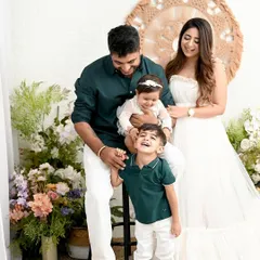 A picture-perfect family of four. The coordinated outfits in white and green, combined with a beautiful floral and boho setup, create a fresh, light, and airy family portrait.