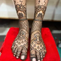 This elegant foot design features large peacock and jhumka (earring) motifs. The pattern extends up from the toes with delicate floral vines, leaving some skin visible for a lighter feel.