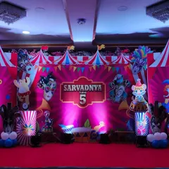 A full stage setup for a circus and masquerade theme party. The red backdrop with circus tent details, character cutouts, and masks creates a vibrant and theatrical setting for a 5th birthday.