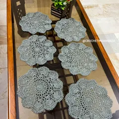 This set of six grey placemats features an intricate, openwork floral design. They are perfect for protecting your table while adding a touch of handmade elegance.