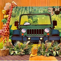 A fantastic safari jeep photo booth, perfect for a jungle-themed party. The setup is complete with a life-sized giraffe, lush faux foliage, and balloon decorations, creating an amazing photo opportunity for guests.