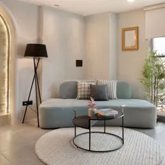 This sitting area in a modern office space elevates the art of the meeting. The curved sofa, tripod floor lamp, and textured rug create a sophisticated yet comfortable atmosphere for collaboration.