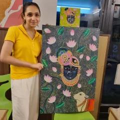 A student proudly displays her large, intricate Pichwai-style painting of Lord Krishna, a beautiful piece she created in my class.