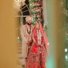 A candid, through-the-foliage shot of the couple sharing a smile during their wedding. This artistic framing adds depth and a sense of intimacy to the moment.