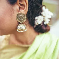 Beauty is in the details. This shot highlights a traditional gold jhumka earring and the delicate gajra of fresh flowers in the bride's hair, elements that define a classic Indian bridal aesthetic.