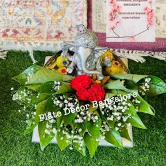 A simple yet elegant pooja platter with a silver Ganesha idol, decorated with red carnations, baby's breath, and betel leaves.