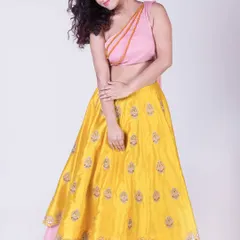 A bold and modern take on the lehenga, this set features a bright yellow embroidered skirt paired with a chic pink one-shoulder crop top. This is a perfect outfit for a vibrant mehendi or sangeet party.