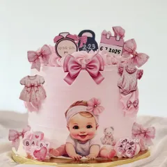 The sweetest cake to welcome a new baby girl. This pink cake is adorned with edible illustrations of baby clothes, bows, a calendar with the birth date, and a clock showing the time of birth.