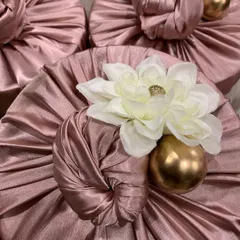 Luxurious pink satin Furoshiki wrapping, topped with a white flower and a golden accent ball. This style of gift wrapping adds a touch of class to any present.