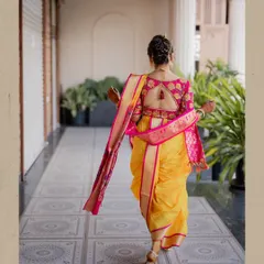 A stunning back shot of the bride in her yellow and pink nauvari saree, showing the intricate design of her blouse and her graceful posture.
