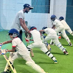 Teamwork and fundamentals are at the heart of my coaching. Here, a group of young players works on their batting stance in our spacious indoor facility, ensuring they learn and grow together.