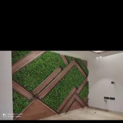 An indoor feature wall with a geometric pattern. I used dark wood framing to create angular sections, which are then filled with dense artificial greenery for a modern, textured look.