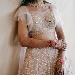 A close-up shot focusing on the bride's gorgeous Sangeet outfit. The mirror work on the blouse and her intricate mehndi are beautifully detailed.