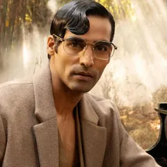 A striking male portrait for John Jacobs, focusing on the details of the classic metal-frame eyeglasses.