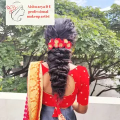 A thick, textured fishtail braid adorned with a beautiful red floral hair accessory. This style is perfect for a traditional South Indian look and works beautifully with sarees and lehengas.