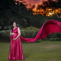A dramatic outdoor shot featuring a mother-to-be in a satin gown with a long, flowing train catching the wind. This technique adds movement and a touch of glamour to the maternity portrait.