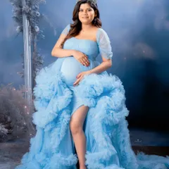 A fairytale moment captured in our studio. This mom-to-be looks like a queen in a ruffled light blue gown, complete with a tiara and a dreamy, cloud-like background.