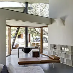 The bedroom in 'The Leaf House' is a serene space where the interior flows into the exterior. The unique form of the roof and the large glass openings make you feel completely immersed in nature.