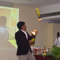 A moment of pure performance during a workshop. Our bartender demonstrates a fire flair move, juggling flaming bottles to the delight of the audience. This is the energy we bring.