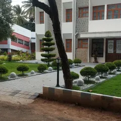 Formal landscaping for an institutional building, featuring a paved walkway, manicured lawns, and topiary shrubs. The design is clean, orderly, and professional.
