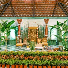 This Muhurtham setup reimagines tradition. We skipped a conventional mandap, using lush banana plants, antique temple pillars, and a stunning illustrated backdrop to create a stage that is both grand and deeply personal.