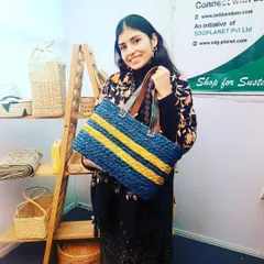 A customer showcasing our striped blue and yellow tote bag, made from woven natural fibers with durable leather-style straps. This spacious and stylish bag is perfect for work, shopping, or as a chic everyday carryall.