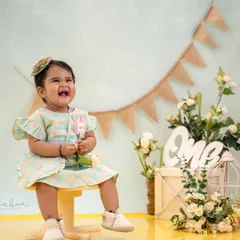 A burst of pure happiness. This little girl's laughter filled the studio during her first birthday photoshoot, set against a charming rustic backdrop.