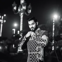 A dramatic black and white photo that highlights the silhouette of the Indo-Western jacket against the night lights. It's a modern take on royal attire.