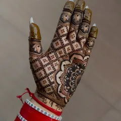 A stunning back-of-hand design with a full 'jaal' or net pattern and a bold mandala at the wrist. The bride's red 'chooda' bangles add to the festive look.