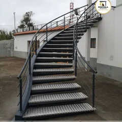 A practical and durable outdoor spiral staircase featuring anti-slip checkered plate treads. This design is ideal for providing access to rooftops or terraces in commercial or industrial settings where safety is paramount.