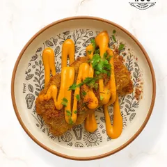 This dish features soft, pan-fried cottage cheese seasoned with a crunchy, aromatic dukkah spice blend from the Middle East. It is served with a creamy sauce and fresh herbs for a complex and satisfying flavor.