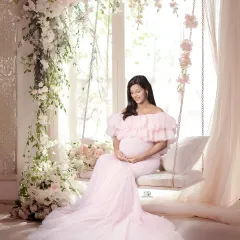 Like a dream. This ethereal studio setup with a floral swing and a flowing pink gown creates a fairy-tale moment. It’s a perfect example of a soft, romantic, and whimsical maternity portrait.