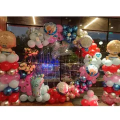 A full view of the red and blue baby shower decor. You can see the balloon columns topped with giant baby boy foil balloons, all framing a beautiful ring backdrop lit with fairy lights.