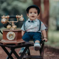 Dressed like a little gentleman with his newsboy cap and suspenders, he looks delighted with the vintage telephone. Using props that spark curiosity is key to getting genuine expressions during a kids photoshoot.