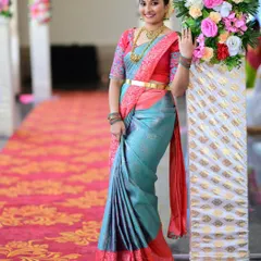 A full-length view of a stunning wedding guest. Her makeup is bright and festive, perfectly complementing her beautiful turquoise and pink silk saree.