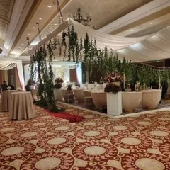 An indoor event setup featuring a canopy decorated with hanging greenery. This style is perfect for creating a more intimate and defined space within a larger banquet hall.