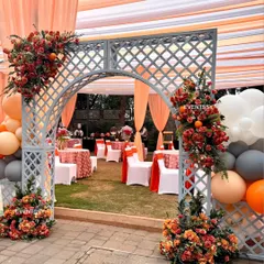 An elegant entrance arch for a baby shower, decorated with fresh flowers and balloons in shades of orange and grey. This archway welcomed guests into the garden party and set the tone for the event.